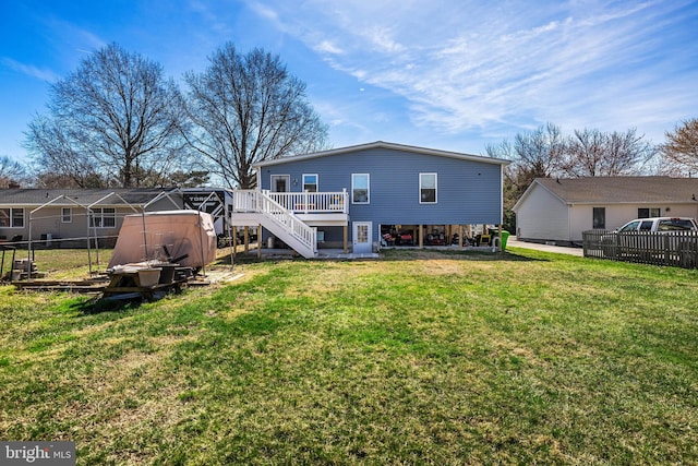 back of property with a wooden deck, a lawn, fence, and stairs