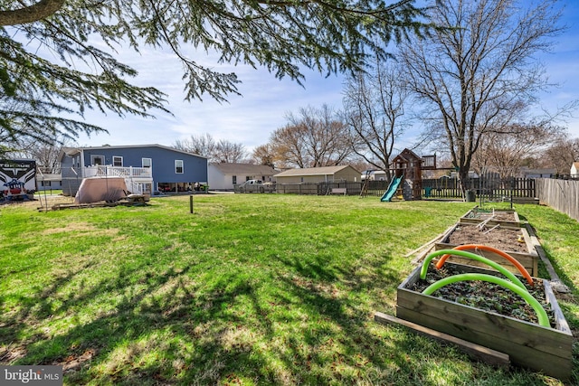 view of yard featuring a garden, a fenced backyard, and a playground