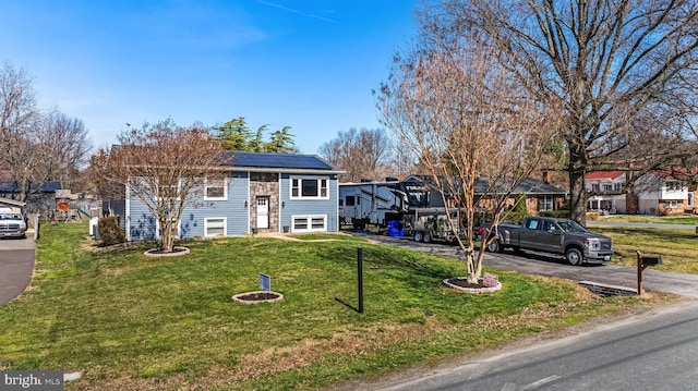 view of front of home with a front yard, a residential view, and solar panels
