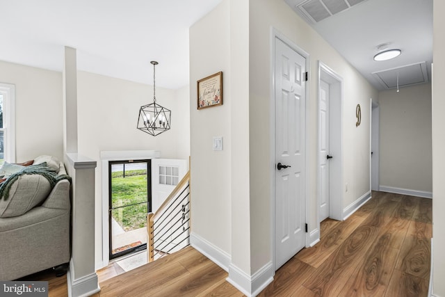 foyer featuring a chandelier, wood finished floors, baseboards, and visible vents
