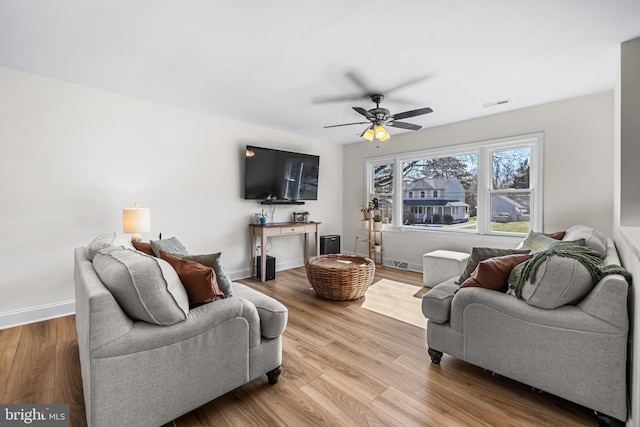 living room with visible vents, ceiling fan, wood finished floors, and baseboards