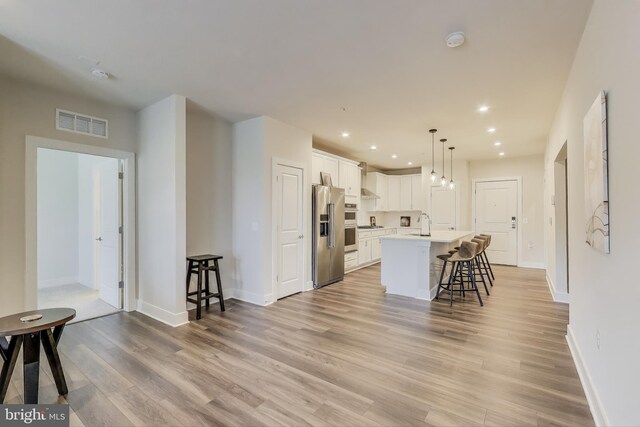 102 Saint Ives Unit 403, National Harbor, MD 20745 - kitchen with a kitchen bar, recessed lighting, visible vents, light wood-style flooring, and appliances with stainless steel finishes