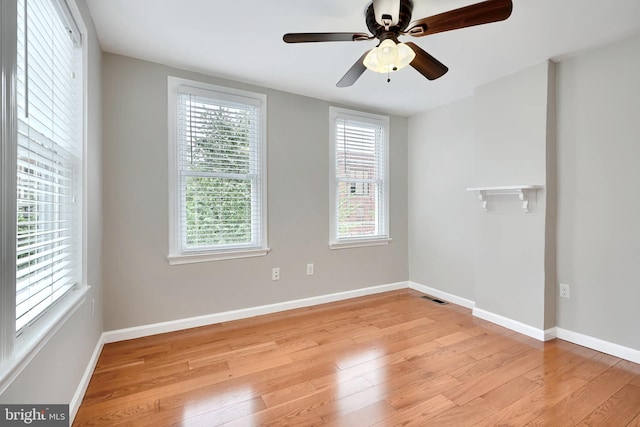 unfurnished room with light wood finished floors, healthy amount of natural light, baseboards, and a ceiling fan