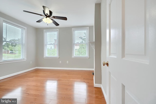 spare room featuring light wood finished floors, baseboards, and a ceiling fan