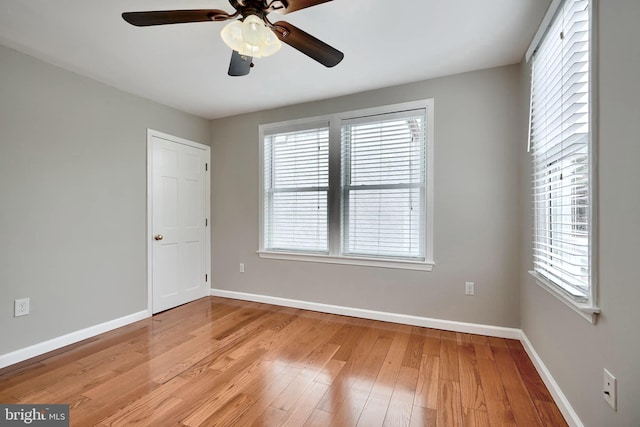 spare room with baseboards, healthy amount of natural light, light wood-style flooring, and ceiling fan