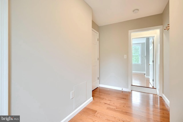 spare room with light wood-style floors, a smoke detector, and baseboards