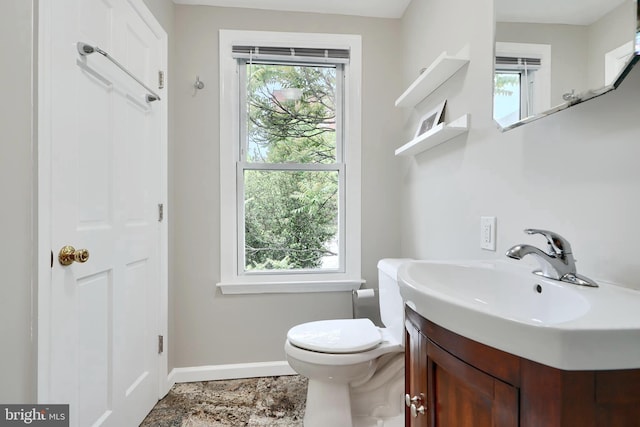bathroom with baseboards, toilet, and vanity