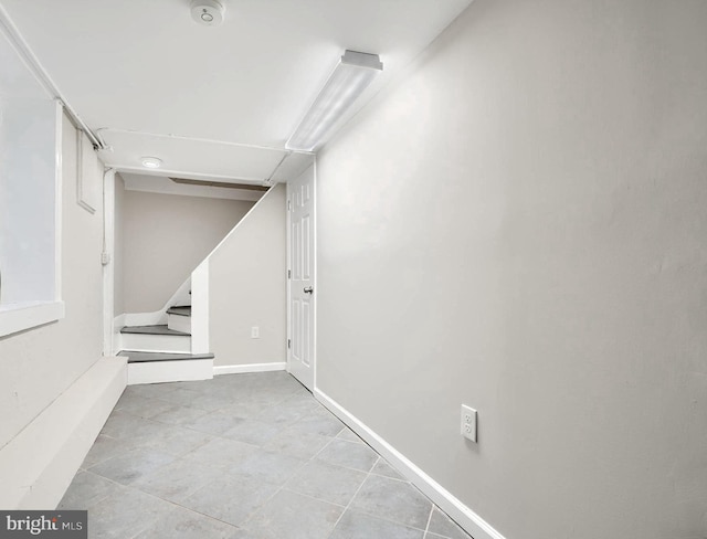finished below grade area featuring stairs and tile patterned flooring