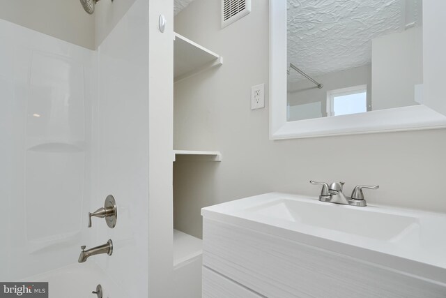 full bathroom with shower / washtub combination, vanity, and a textured ceiling