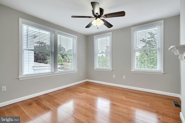 spare room featuring baseboards, light wood-style floors, and ceiling fan