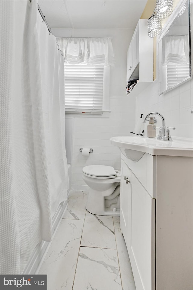full bathroom featuring marble finish floor, shower / bathtub combination with curtain, toilet, and vanity