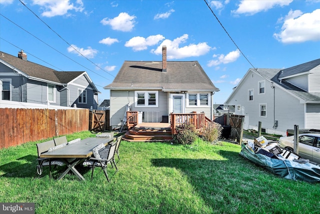 back of house with fence, a wooden deck, a lawn, a gate, and a chimney