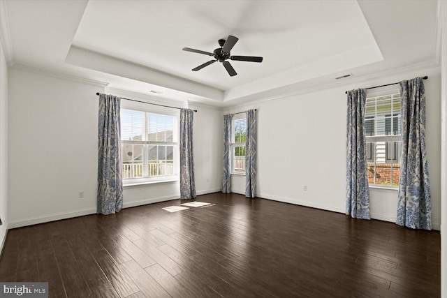 spare room featuring visible vents, wood finished floors, baseboards, a tray ceiling, and a ceiling fan
