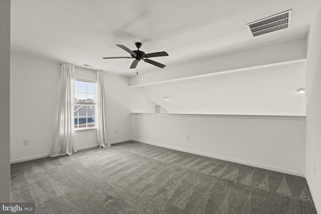carpeted spare room featuring ceiling fan, visible vents, baseboards, and vaulted ceiling