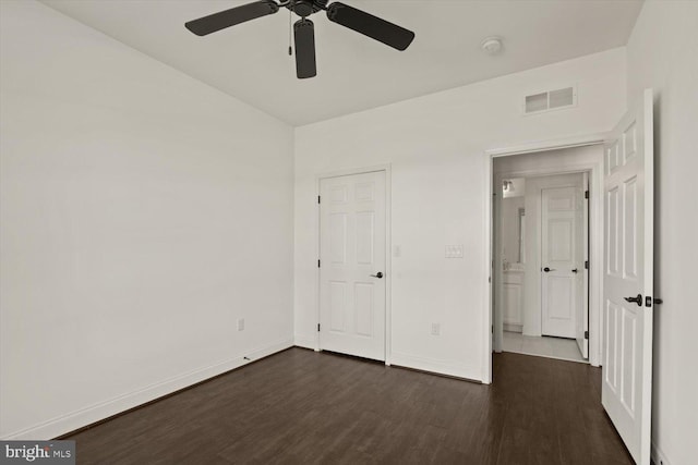 unfurnished bedroom with baseboards, ceiling fan, dark wood finished floors, and visible vents
