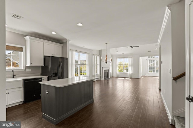 kitchen featuring white cabinets, a sink, light countertops, open floor plan, and black appliances