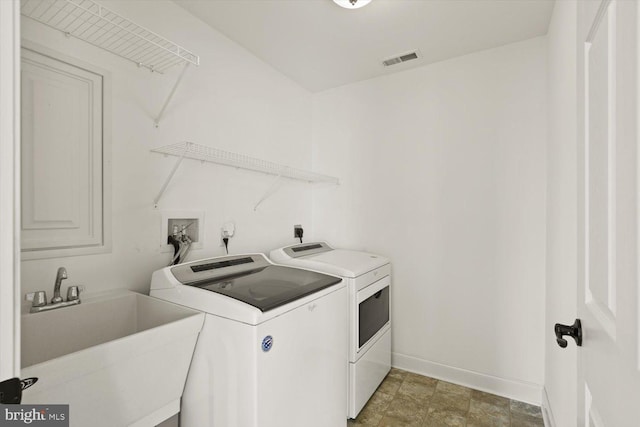 washroom with laundry area, visible vents, baseboards, separate washer and dryer, and a sink