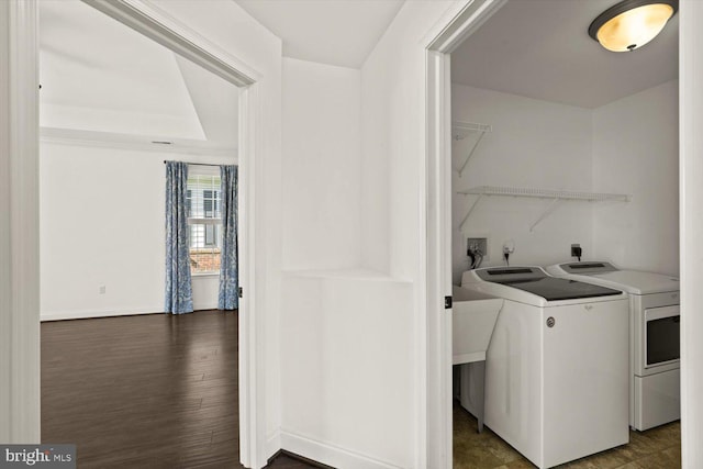 washroom featuring laundry area, baseboards, dark wood-type flooring, and separate washer and dryer