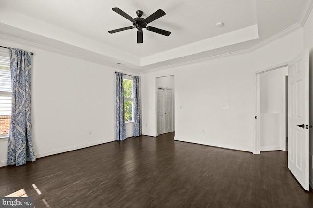 empty room featuring baseboards, a ceiling fan, a raised ceiling, and dark wood finished floors