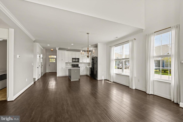 unfurnished living room featuring ornamental molding, a notable chandelier, and a healthy amount of sunlight