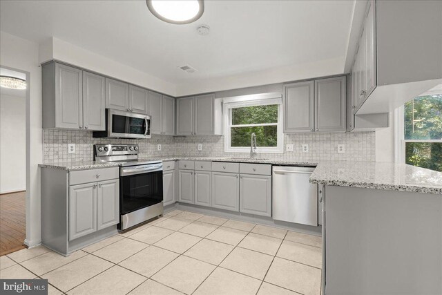 17 Alexandria Overlook Dr, Oxon Hill, MD 20745 - kitchen featuring light tile patterned flooring, gray cabinets, a sink, stainless steel appliances, and tasteful backsplash