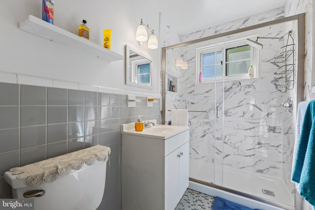 full bathroom featuring tile walls, vanity, toilet, and a marble finish shower