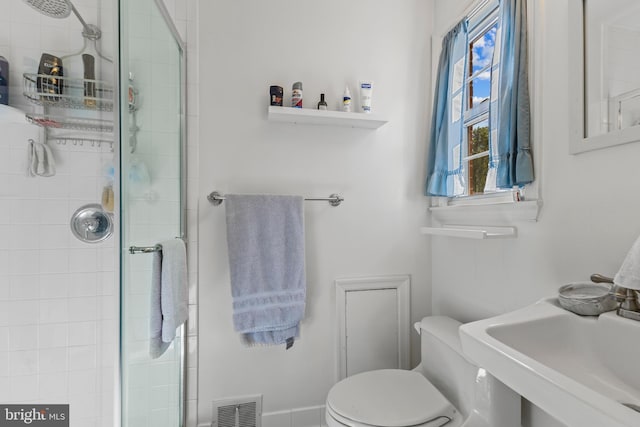 bathroom featuring toilet, tiled shower, and visible vents