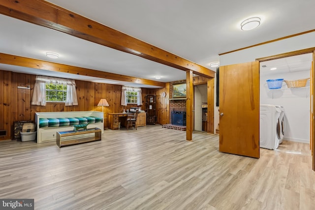 living room with beam ceiling, wood finished floors, a fireplace, wooden walls, and independent washer and dryer