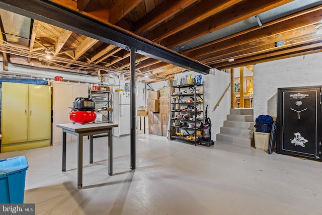 unfinished basement featuring freestanding refrigerator and stairway