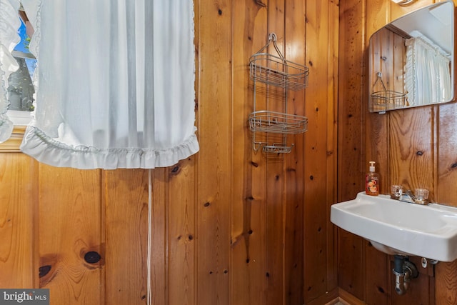 bathroom featuring wood walls and a sink