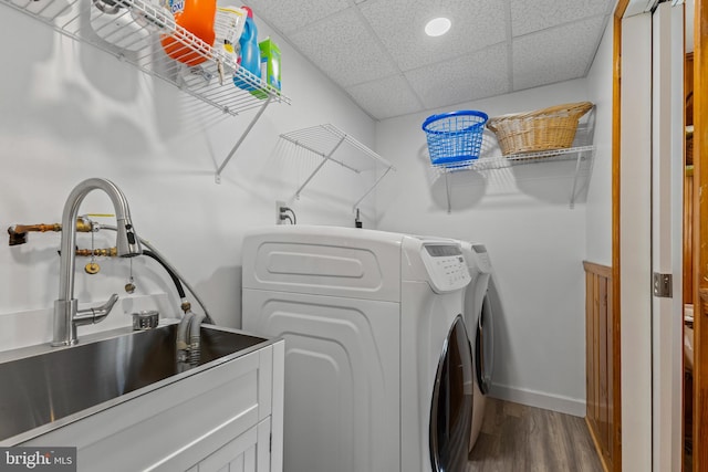 clothes washing area with independent washer and dryer, laundry area, a sink, baseboards, and dark wood-type flooring