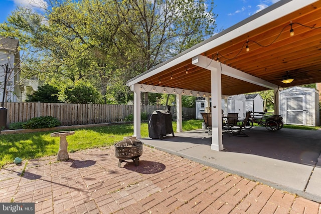 view of patio / terrace featuring a storage shed, an outdoor structure, a fenced backyard, and an outdoor fire pit