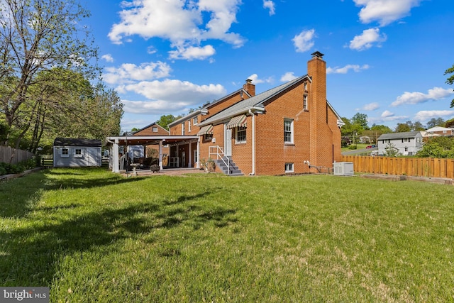 back of property featuring brick siding, a storage shed, a fenced backyard, a chimney, and a yard