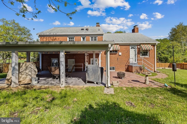back of house with fence, brick siding, a chimney, a patio, and a yard