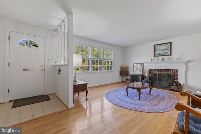 entryway featuring a brick fireplace, baseboards, and wood finished floors