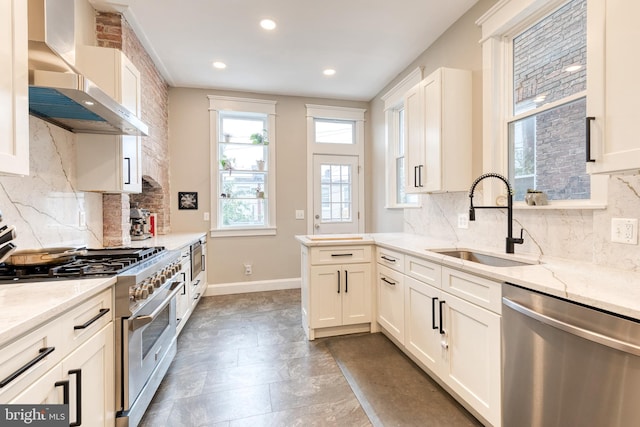 21 N Collington Ave N, Baltimore, MD 21231 - kitchen featuring appliances with stainless steel finishes, wall chimney range hood, a sink, decorative backsplash, and recessed lighting