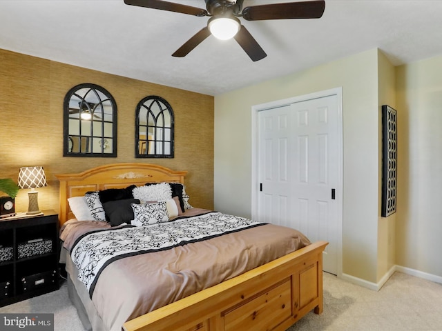 bedroom with light colored carpet, an accent wall, baseboards, and ceiling fan