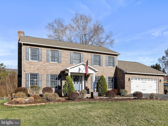 colonial house with a front yard, an attached garage, brick siding, and a chimney
