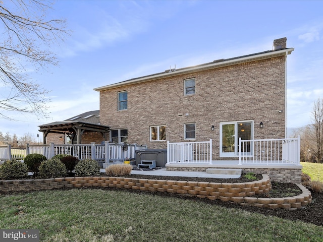 back of property featuring a gazebo, brick siding, a chimney, and a hot tub