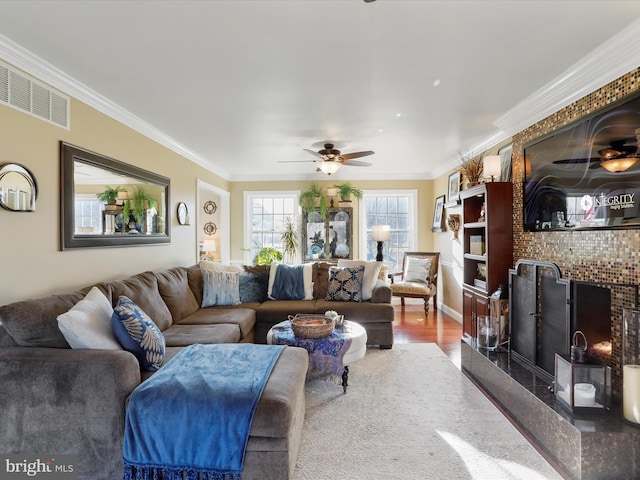living room with visible vents, wood finished floors, ceiling fan, and ornamental molding