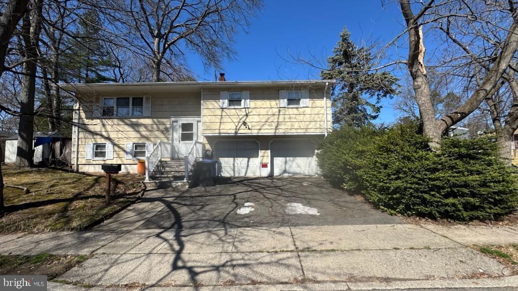 back of property featuring a chimney, an attached garage, and aphalt driveway