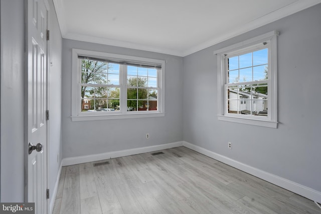 empty room with baseboards, crown molding, visible vents, and light wood finished floors