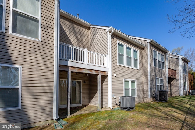 rear view of property with central AC and a yard