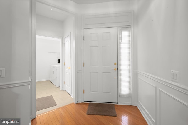 entryway with a decorative wall, a wainscoted wall, and light wood-style floors