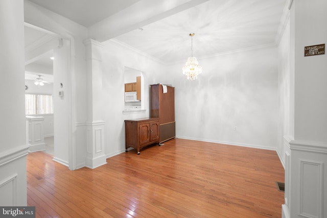 unfurnished dining area featuring ornamental molding, light wood-type flooring, and ceiling fan with notable chandelier