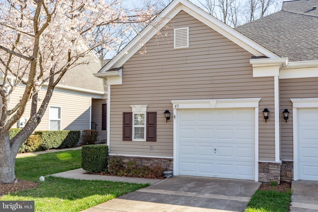 view of front facade featuring stone siding, an attached garage, concrete driveway, and roof with shingles