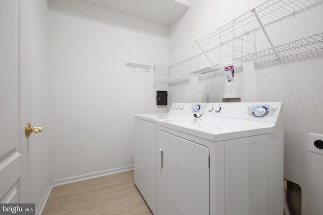 washroom featuring washer and clothes dryer, baseboards, light wood-style floors, and laundry area