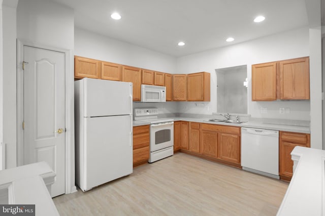 kitchen featuring light wood-style flooring, light countertops, a sink, and white appliances