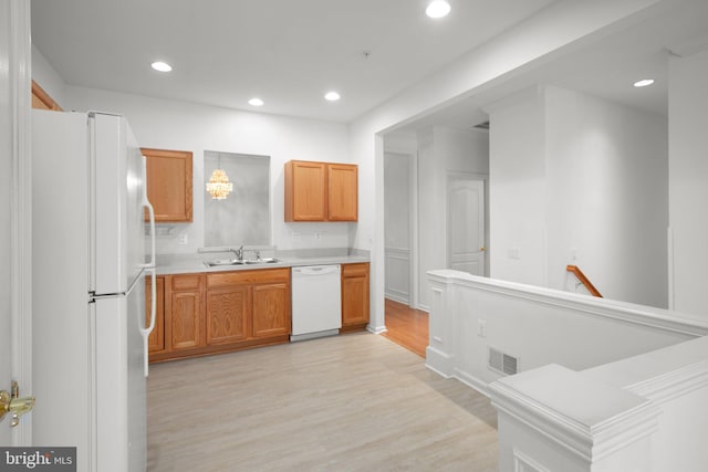 kitchen with light countertops, white appliances, recessed lighting, a sink, and light wood-style floors