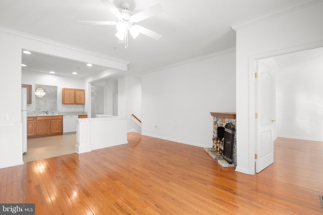 unfurnished living room with a sink, ornamental molding, light wood-style flooring, and ceiling fan
